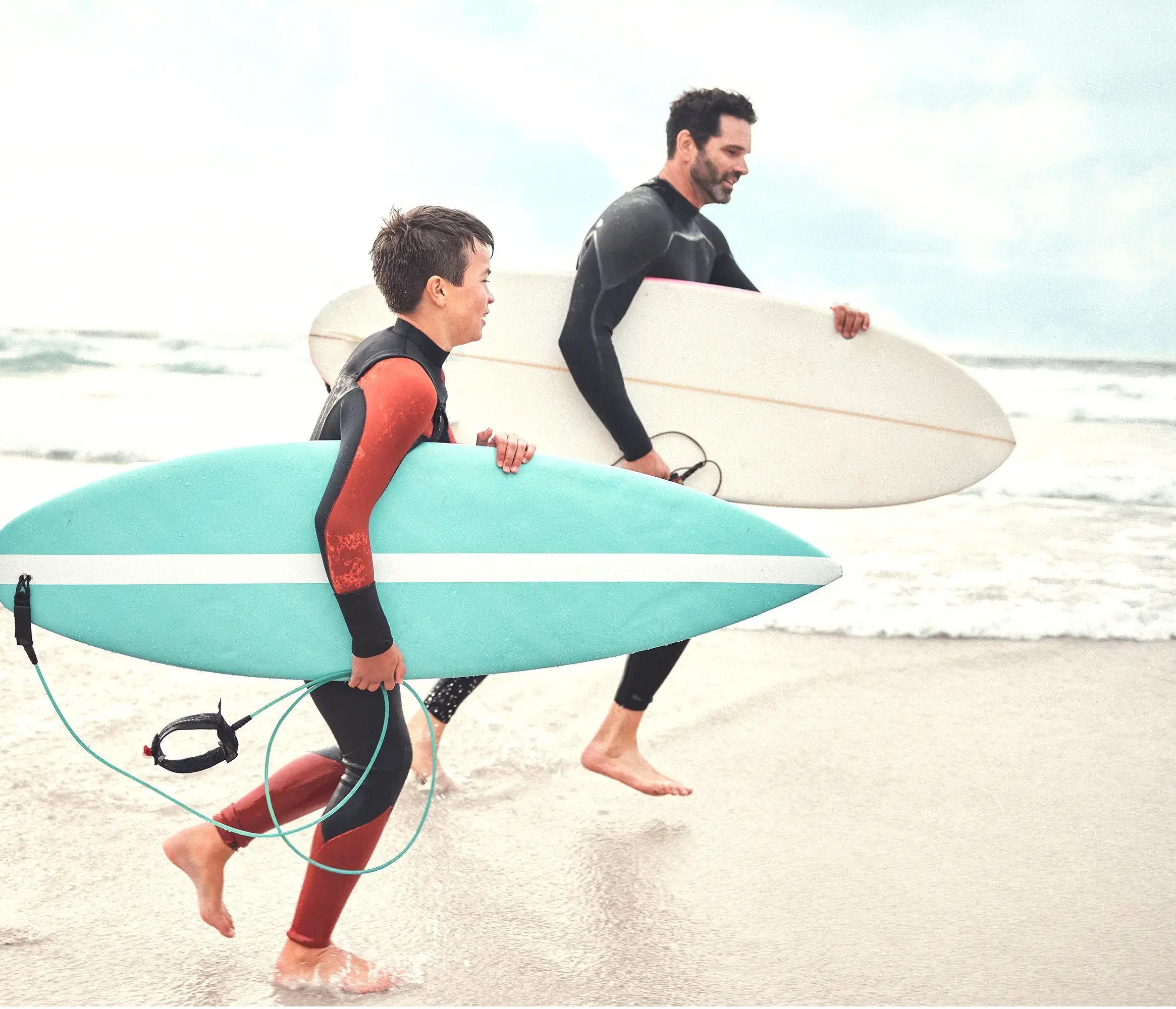 Thrive-dad and son running on beach surfboards